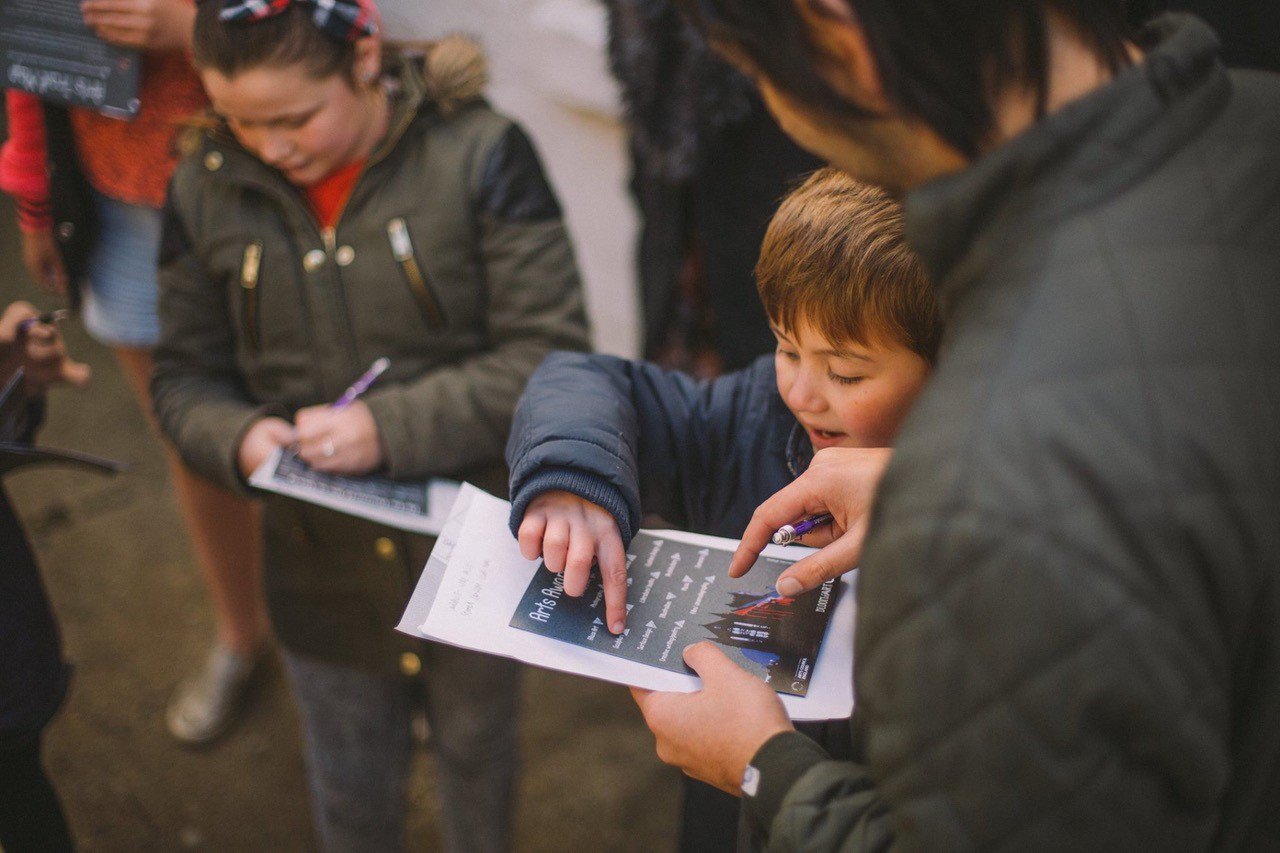 Child pointing at writing on a piece of paper.